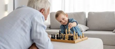 The adorable little boy playing chess with his grandfather